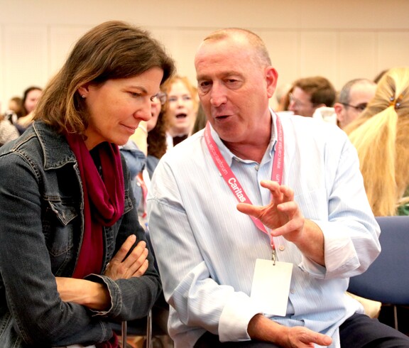 Eine Frau und ein Mann sitzen auf Sesseln und unterhalten sich.