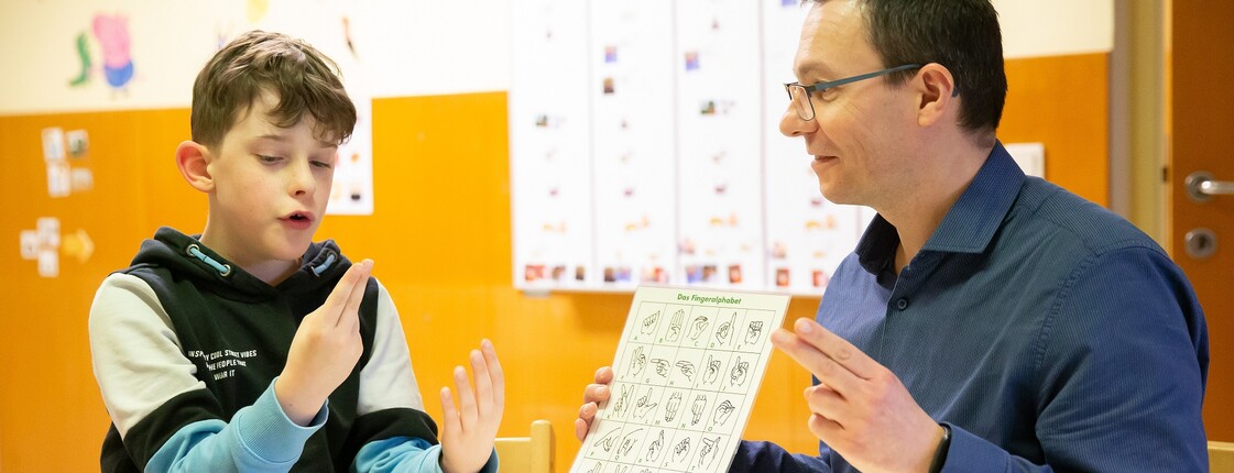 Luan und Hortleiter Wolfgang Holzinger beim Fingeralphabet. Eines der Interessen des Neunjährigen. 