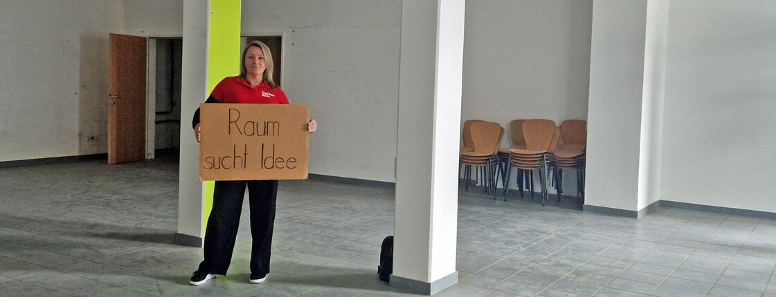 Frau steht in leerem Raum mit Schild "Raum sucht Idee"