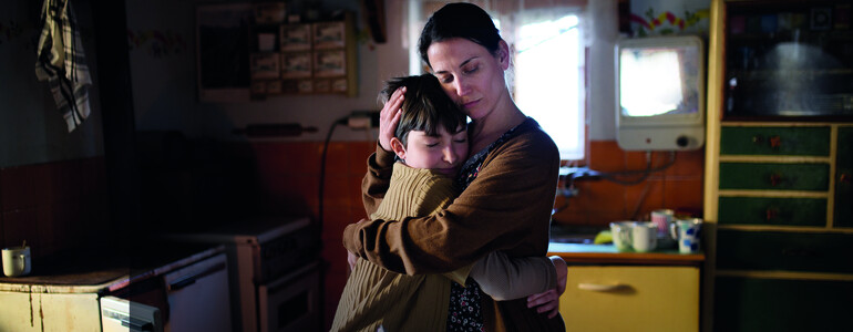 Portrait of sad poor mature mother hugging small daughter indoors at home, poverty concept.