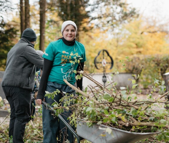 Jugendliche mit Scheibtruhe in der abgeschnitte Zweige sind.