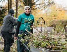 Jugendliche mit Scheibtruhe in der abgeschnitte Zweige sind.