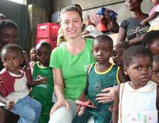 Andrea Fellner sitzt inmitten einer Gruppe von Kindern in der Ernährungsstation in N’sele und lächelt in die Kamera