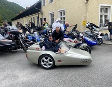 Eine Beiwagenmaschine und mehrere Motorräder vor einem gelben Gebäude
