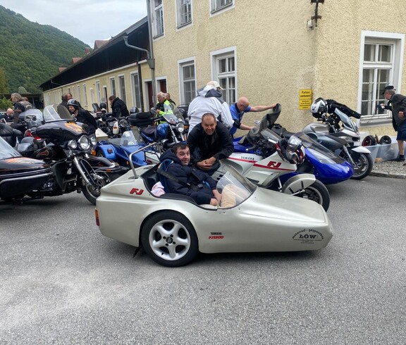 Eine Beiwagenmaschine und mehrere Motorräder vor einem gelben Gebäude