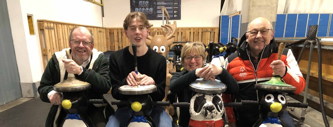 Vier Stockschützen mit Eislauf-Pinguinen