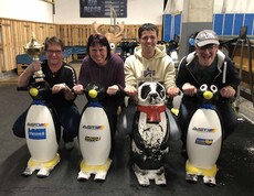Vier Personen mit Eislauf-Pinguinen