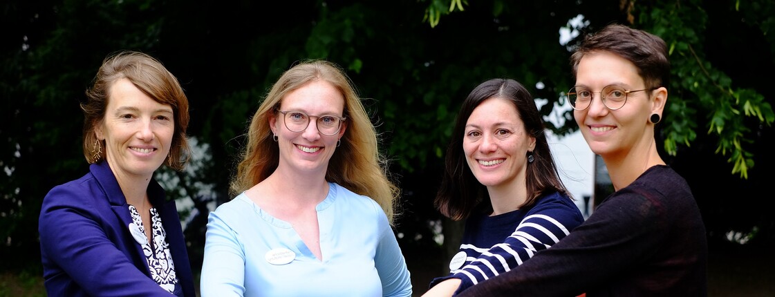 4 Personen stehen im feien zusammen und stecken die Arme nach vorne und die Hände berühren sich.