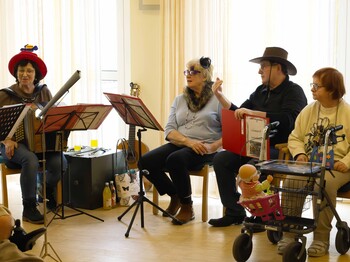 Zwei Musikerinnen, ein Musiker und eine Zuhörerin sitzen im Halbkreis