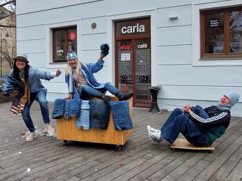 Drei Personen präsentieren vor einem Geschäft Jeans für eine Jeans-Aktion.