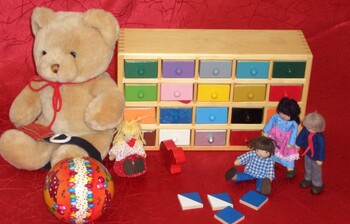 Verschiedenes Spielzeug, darunter ein Bär, ein Ball und kleine Holzpüppchen