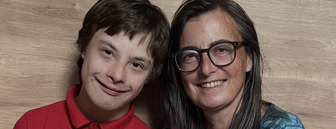 Links im Bild ein Jugendlicher im roten T-Poloshirt, rechts dabenben eine Frau mit langen braunen Haaren, einer Brille und einem blau-gestreiften Pullover