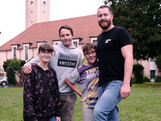Ein Betreuer spielt Fußball mit drei Kindern vor der Kirche in St. Isidor.