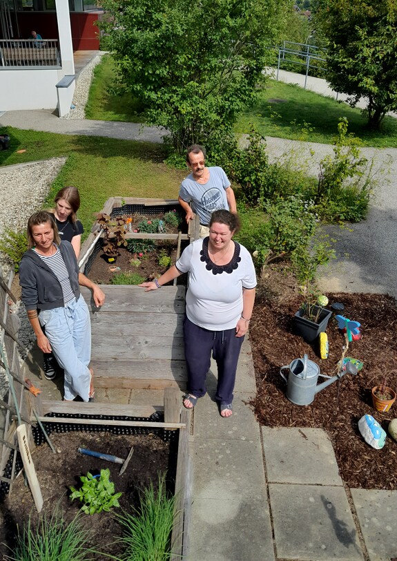 Vier Personen stehen um ein Hochbeet herum.