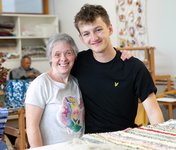 Ein junger Mann und eine ältere Dame lächeln glücklich in die Kamera