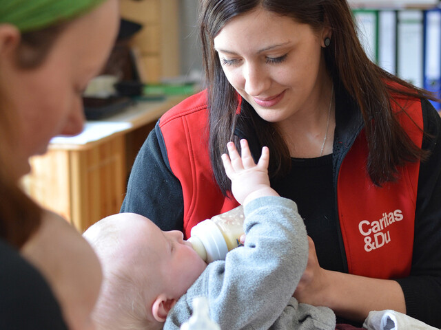 Eine Caritas-Mitarbeiterin füttert ein Baby