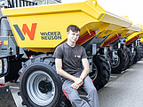 Ein junger Man sitzt auf dem Reifen eines Baustellenfahrzeugs