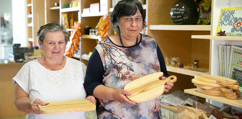 Zwei Frauen halten selbst gemachte Holz-Jausen-Brettl in die Kamera.