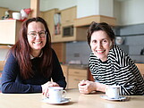 Zwei Frauen sitzten an einem Tisch bei einer Tasse Kaffee.