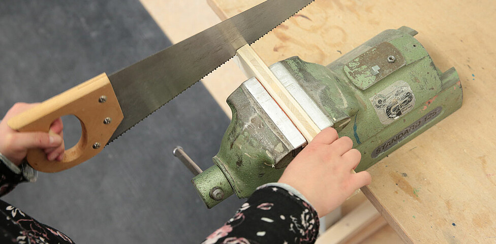 Mit einer Handsäge wird Holz geschnitten