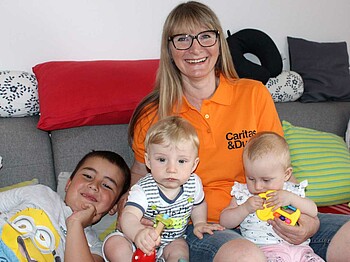 Eine Frau sitzt mit drei Kindern auf der Couch